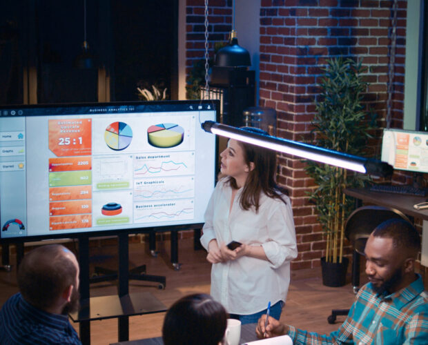 Team working on company research analytics presentation in business meeting, planning marketing strategy. Coworkers discussing sales statistics diagrams and charts at digital board